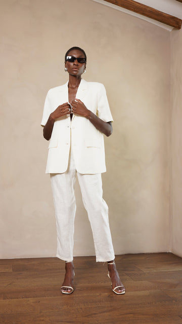 Person wearing a white suit and sunglasses in a minimal indoor setting