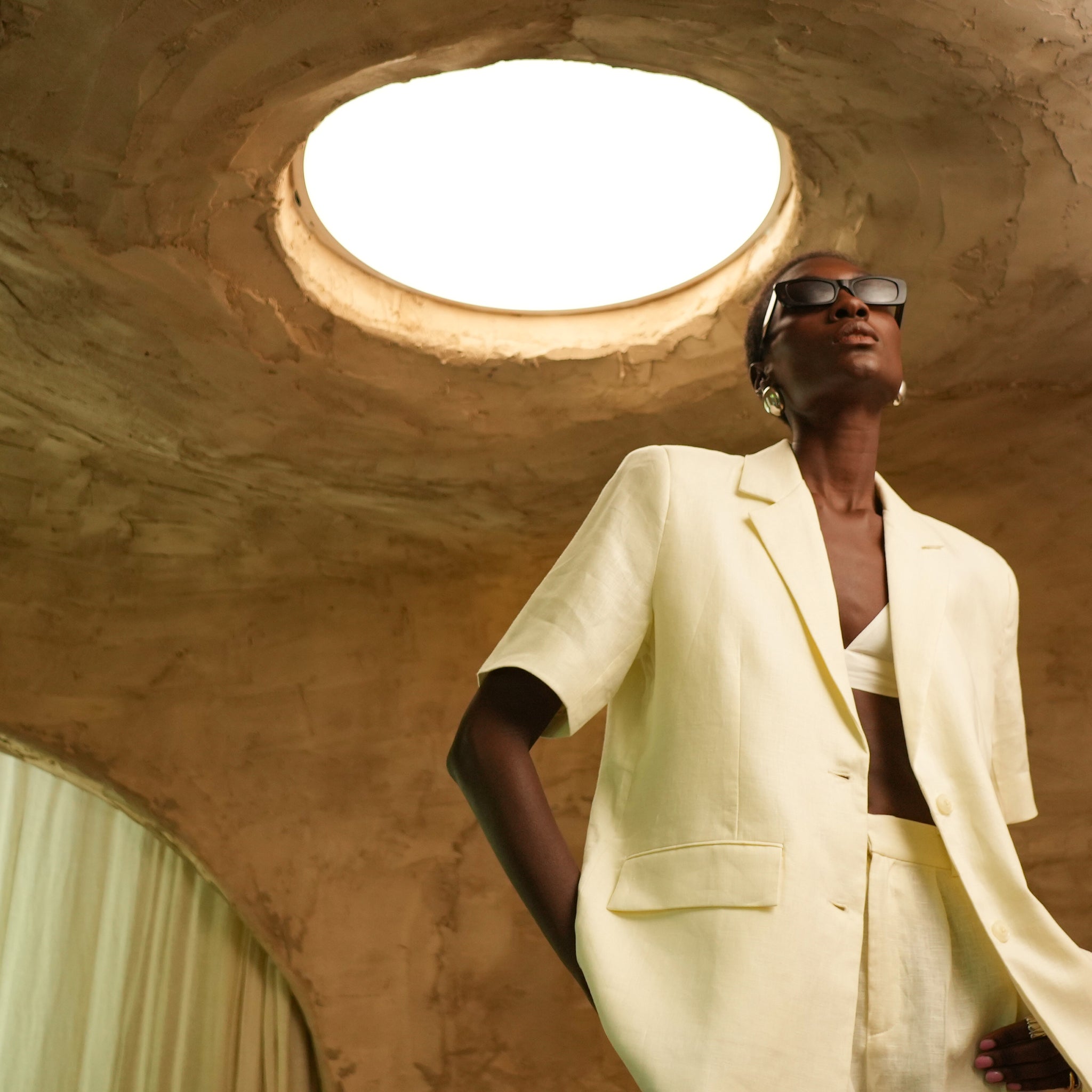 Person wearing a light-colored suit in a room with a skylight.