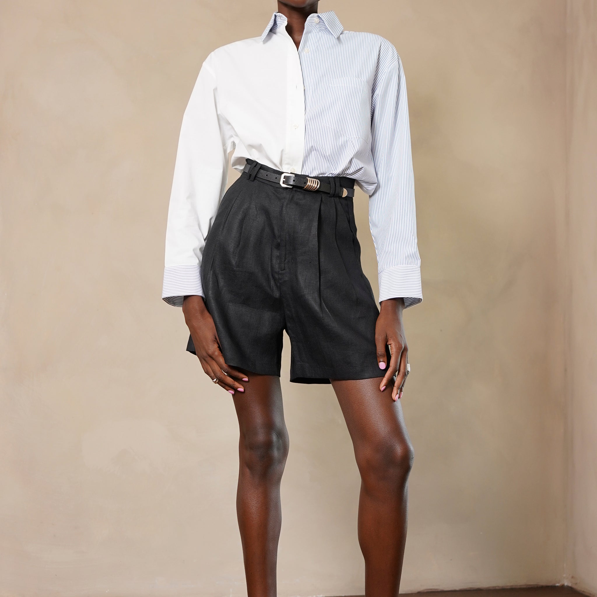 Person wearing a white shirt and black shorts against a beige wall.